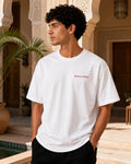 T-shirt blanc minimaliste MarocGear avec inscription Morocco Always, présenté dans un décor de riad marocain premium.