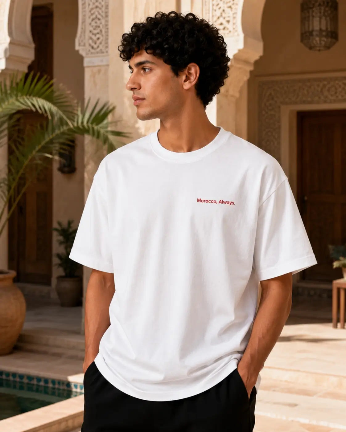 T-shirt blanc minimaliste MarocGear avec inscription Morocco Always, présenté dans un décor de riad marocain premium.