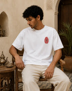 T-shirt blanc MarocGear avec badge rouge marocain, porté dans un décor de riad premium.