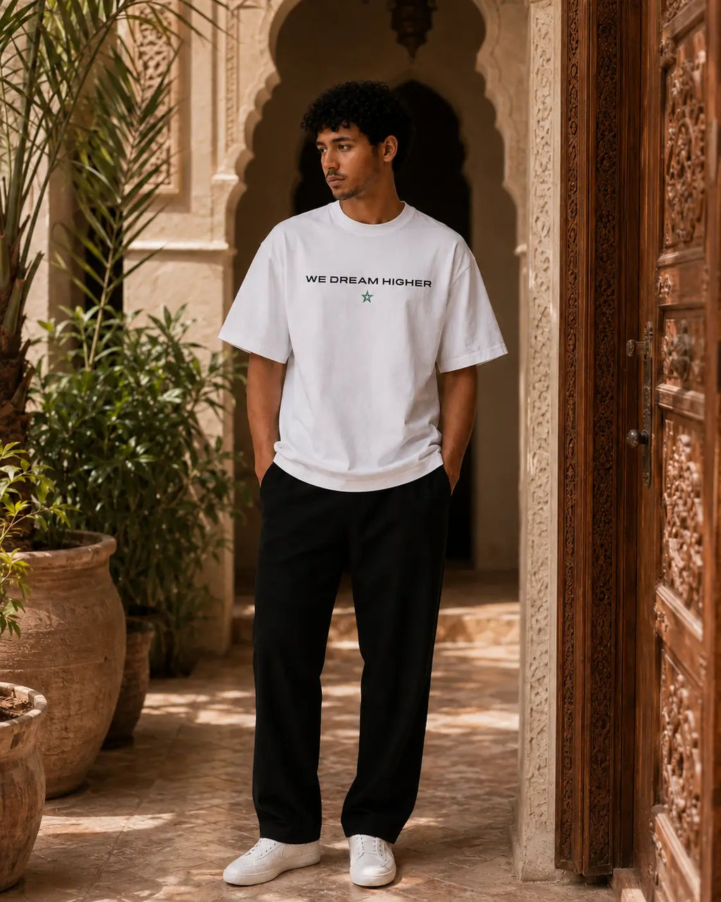 T-shirt blanc MarocGear Maroc 2026, design supporter avec slogan We Dream Higher et visuel premium dans un riad marocain.